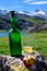 Green bottle and glass of natural Asturian cider made fromÂ fermented apples with view on Covadonga lake and tops of Picos de